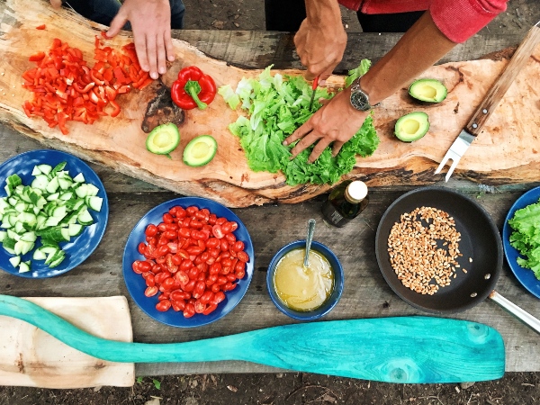 Top-down view of people chopping vegetables and putting in bowls